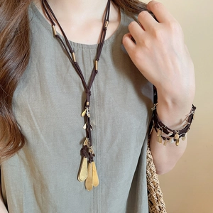 Detail of vintage layered brown leather necklace with golden water drop pendants