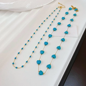 Detail of gold-plated bohemian necklace with turquoise beads and heart charms