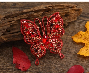 Gros plan d'une broche papillon vintage avec cristaux rouges sur fond de bois