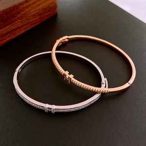 Macro detail of H-shaped letter clasp on gold and silver plated cubic zirconia bracelets