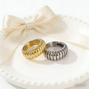 Detail of gold and silver stainless steel ribbed rings on a white decorative porcelain plate
