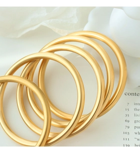 Macro shot of matte gold bangle set with fine frosted texture and elegant metallic finish