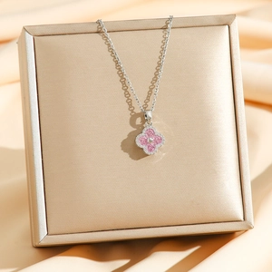 Detail of silver clover necklace with pink zircon crystals on a luxury jewelry box