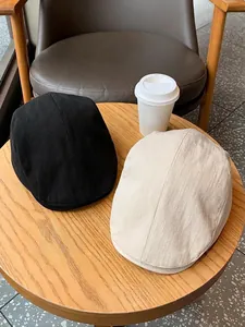 Classic vintage newsboy caps in black and beige twill fabric on a wooden table
