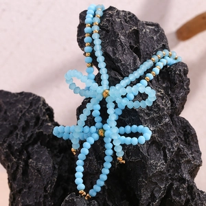 Close-up of blue frosted beads and gold accents in a bow shape on black volcanic stone