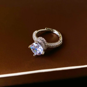 Détail macro d'une bague argentée ajustable avec un grand zircon brillant et pavé de pierres