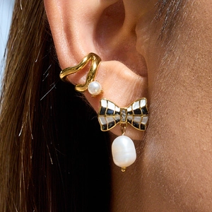 Elegant gold bow earrings with black enamel pattern and baroque pearls on model