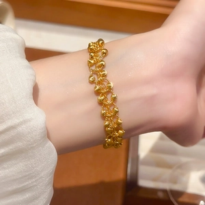 Macro detail of 24K gold plated geometric beads woven bracelet on a person's wrist