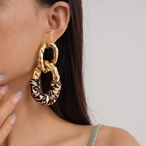 Detail of gold hammered metal and leopard print fabric hoop earrings on a model