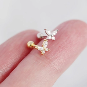 Macro shot of silver butterfly ear studs with sparkling zircons on a fingertip