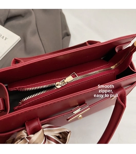 Détail macro de la fermeture éclair dorée et du foulard en soie sur sac à main rouge