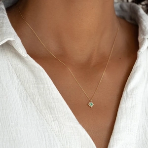 Close-up of starburst pendant with green gemstone and white diamonds on a gold chain