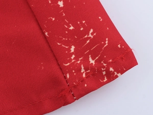 Detailed close-up of red fabric with white splash print and neat stitching craftsmanship