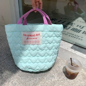 Détail d'un sac à main bleu clair matelassé avec couture cœur et étiquette de marque
