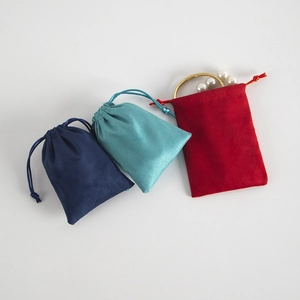 Detail of soft velvet drawstring jewelry pouches in navy blue, cyan, and red colors