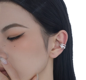 Detailed close-up of a silver irregular lava texture ear cuff with black gemstone on ear