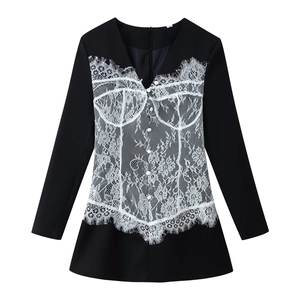 Détail de dentelle blanche sur une robe blazer noire ajustée à col en V profond