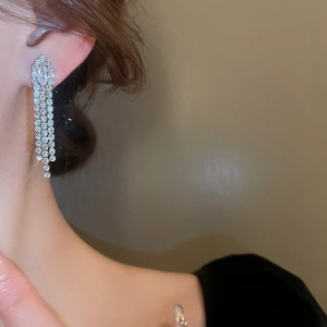 Detail of silver long tassel earrings with sparkling cubic zirconia on a female model