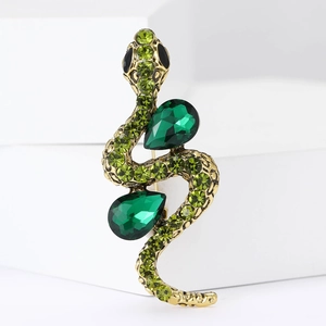 Detail of snake brooch with green rhinestones and emerald drop gems on gold metal