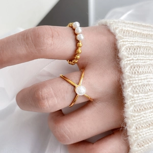 Detail of freshwater pearl pea rings with gold crisscross lines worn on hands