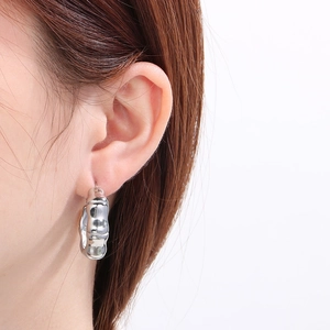 Close-up of silver bamboo joint hoop earrings worn by a model for a stylish metal look