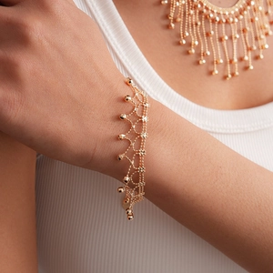 Detailed close-up of a gold mesh bracelet with tassel beads and matching necklace