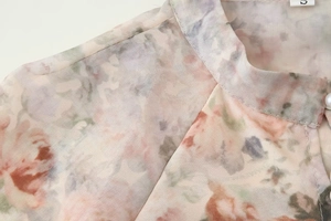 Détail de chemisier à fleurs avec col montant et fermeture boutonnée en perles