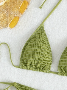 Flat lay of a green halter bikini top with smocked texture and stylish yellow sunglasses