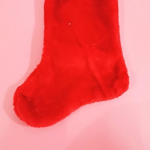 Classic red plush Christmas stocking with white trim on a pink background
