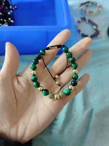 Detail of green tiger eye beaded bracelet with gold accents and adjustable black cord