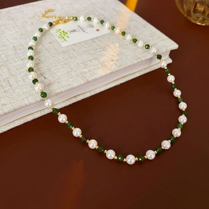 Close-up of pearl and green faceted bead necklace with gold lobster clasp and extension chain