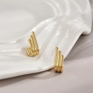 Three-layer matte gold tiered geometric stud earrings on a white textured ceramic tray