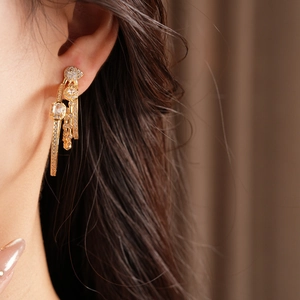Detailed close-up of three-layer gold-plated earrings with pavé crystals on a model