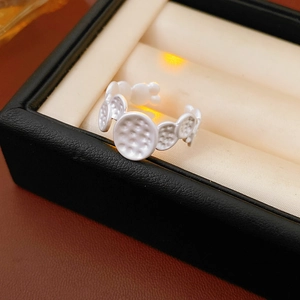 Macro detail of adjustable white enamel ring with hammered texture in a jewelry box