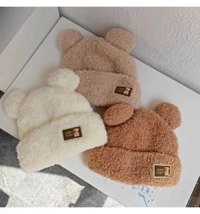 Detail showing plush bear ear knit hats in beige, apricot, and caramel colors with patches
