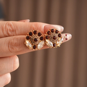 Close-up of vintage gold floral earrings with brown and clear rhinestones detail
