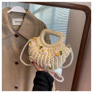 Detail of hand-woven off-white shell bag featuring daisy decor and pearl chain strap