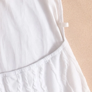 Detail of white knit dress featuring vertical stripes and crochet hollow patterns