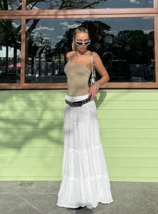 Detail of a white tiered maxi cake skirt paired with a brown one-shoulder top and belt