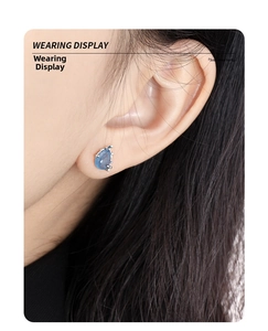 Close-up of S925 sterling silver teardrop stud earrings with blue crystal on model