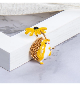 Close-up of cute enamel hedgehog brooch holding a yellow sunflower on a decorative frame