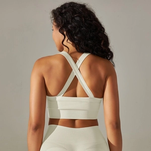 Détail des bretelles croisées d'un soutien-gorge de sport sans couture côtelé crème et legging