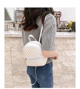 Back view of a mini white PU leather backpack with yellow prints on a model in a cafe