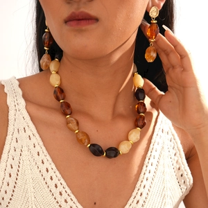 Detail of amber acrylic beaded necklace set with golden spacers and matching earrings