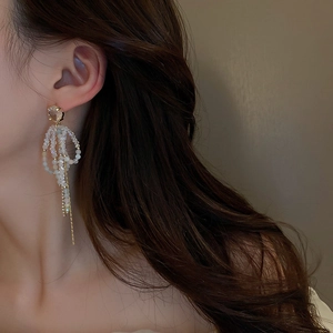 Detail of elegant gold crystal tassel earrings with long chain fringe on model