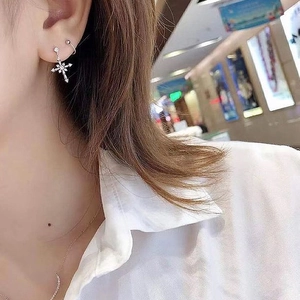 Elegant silver cross earrings with sparkling white crystals worn by a female model