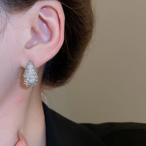 Close-up of elegant pear-shaped zircon stud earrings with silver-tone finish on ear lobe