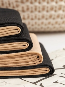 Close-up of stacked black and beige knitted tights showing fabric texture and layers