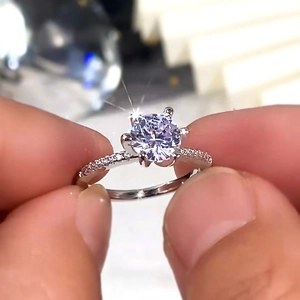 Macro view of six-prong solitaire ring with pave diamonds on a silver band
