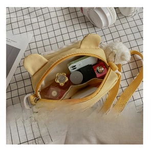 Detail view of yellow canvas crossbody bag with interior pockets and cute decorative ears